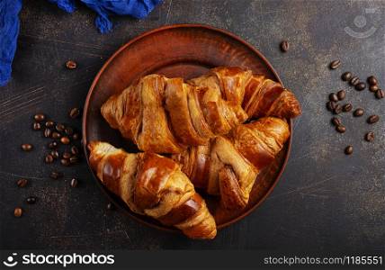 French croissant. Freshly baked croissants with jam on dark stone background.