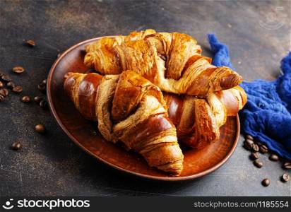 French croissant. Freshly baked croissants with jam on dark stone background.