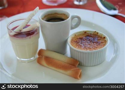 French dessert: Creme brulee, blancmange with berry sauce and meringue and an espresso
