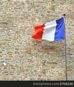 French flag near a stone fortress wall