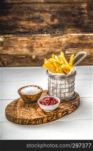 French fries in a basket with salt and ketchup