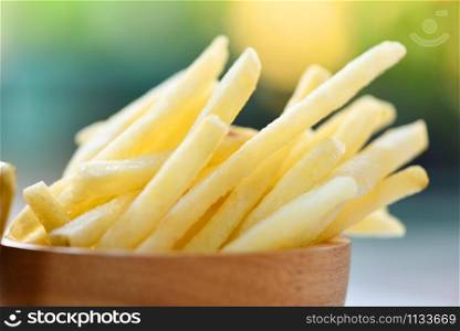 French fries in wooden bowl delicious Italian meny homemade ingredients on table nature green background / Tasty potato fries for food or snack