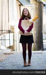 French girl with baguettes on the street side of the city