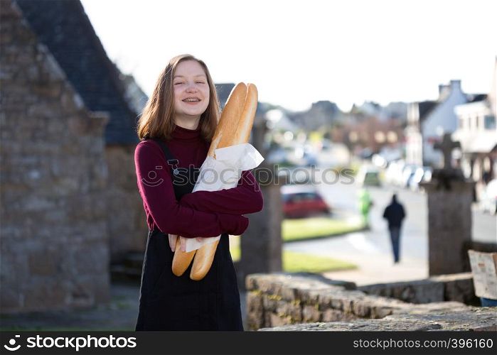 French girl with baguettes on the street side of the city