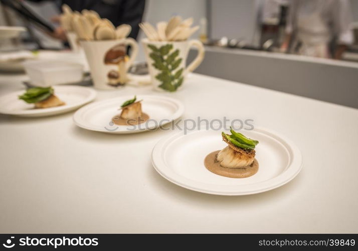 French kitchen with a small portion of salmon and dressing on a white table.