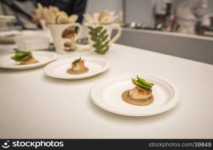 French kitchen with a small portion of salmon and dressing on a white table.