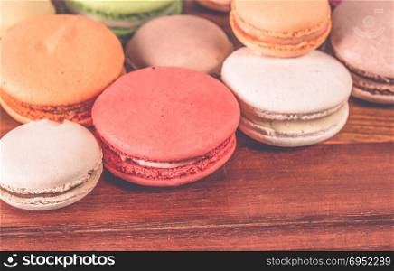 French macarons in cup on wooden background.Toned image