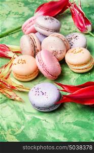 French macaroons with red tulips on a green background. colourful french macaroons