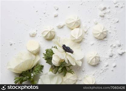 French meringue cookies and flowers on white background ,. White flowers on white background