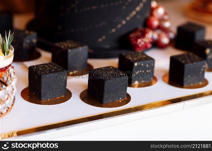 French mousse cake covered with dark chocolate icing. Modern European dessert decorated with gold. selective focus.. French mousse cake covered with dark chocolate icing. Modern European dessert decorated with gold. selective focus