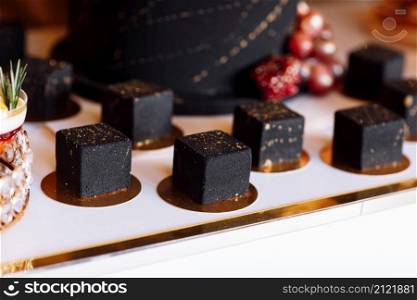 French mousse cake covered with dark chocolate icing. Modern European dessert decorated with gold. selective focus.. French mousse cake covered with dark chocolate icing. Modern European dessert decorated with gold. selective focus