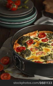 French pie Quiche or Quiche lorraine - traditional open pie with salmon, broccoli, egg, cheese, tomato. Dark and Moody, Mystic Light food photography. 