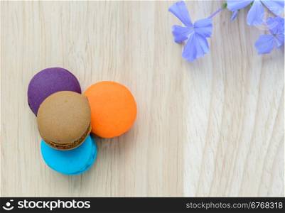 French pink macarons with blue flower on wooden background