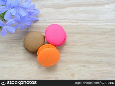 French pink macarons with blue flower on wooden background