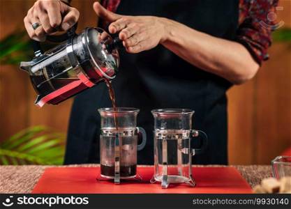 French Press Coffee. Hands of female barista pouring French press coffee in glass coffee mug