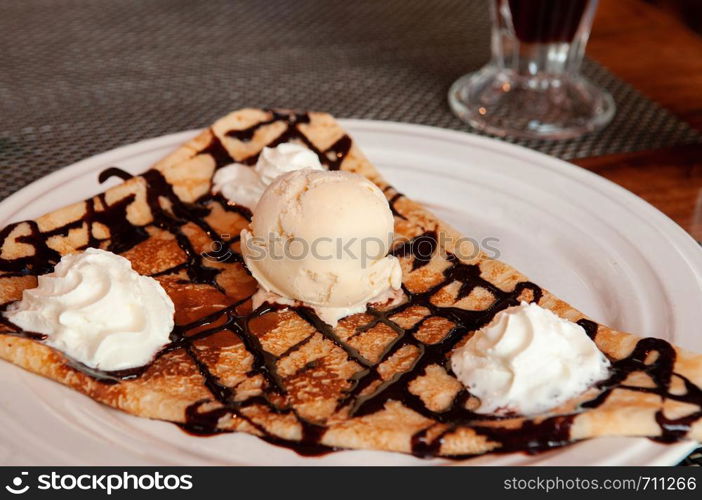 French simple pastry warm crepe with cold vanilla ice cream and whipped cream on white plate - close up