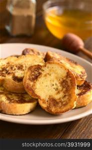 French toast made of baguette, honey and cinnamon powder in the back, photographed with natural light (Selective Focus, Focus on the upper part of the standing toast)