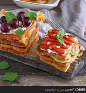 French toast with cottage cheese, strawberries, kiwi a wooden board, close up