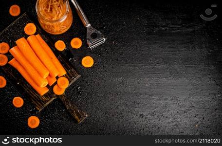 Fresh and canned carrots on a cutting board. On a black background. High quality photo. Fresh and canned carrots on a cutting board.
