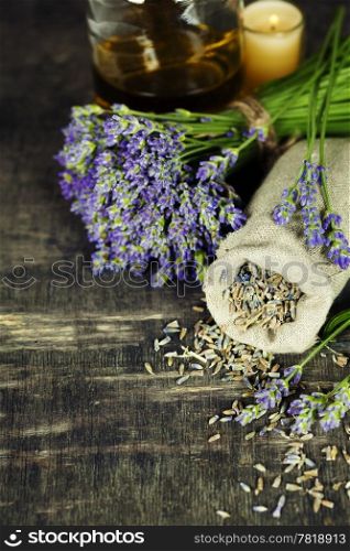 Fresh and dried lavender flowers, essential oil, soap and Herbal massage balls over wooden surface