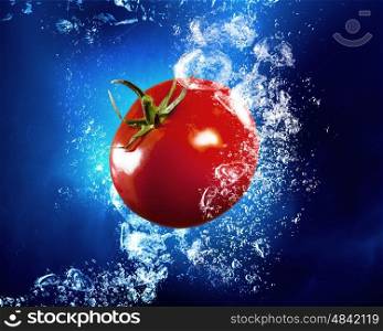Fresh and full of vitamins tomato. Ripe tomato falls under clear blue water