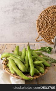 Fresh and raw green broad beans on wooden table.