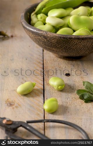 Fresh and raw green broad beans on wooden table.