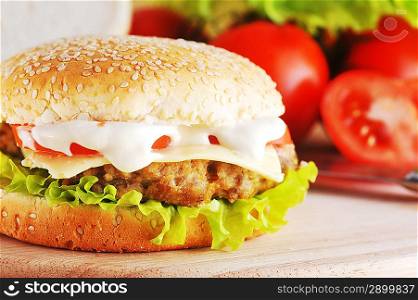 fresh and tasty hamburger with cheese and vegetables lies on plate