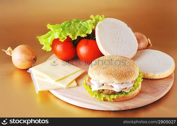 fresh and tasty hamburger with cheese and vegetables lies on plate