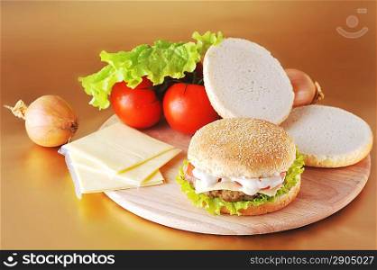 fresh and tasty hamburger with cheese and vegetables lies on plate