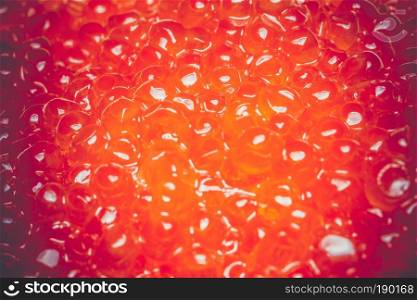Fresh and tasty red salmon caviar close up filtered background.