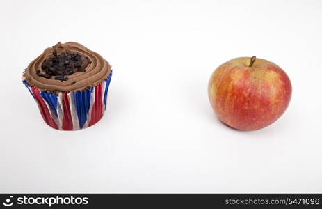 Fresh apple and chocolate cupcake against white background