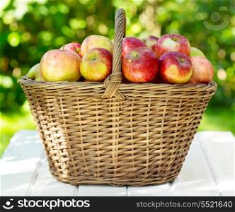 Fresh apples in a basket on wooden table