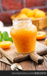 fresh apricot jam in glass bank and on a table