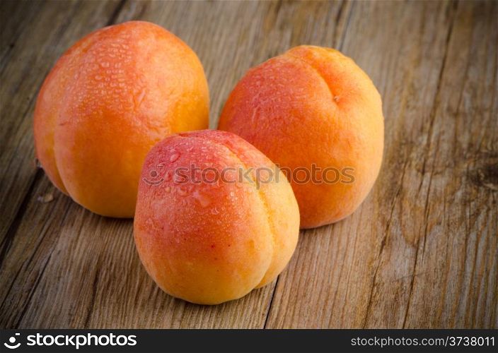 Fresh apricots and leaves over wooden table background.