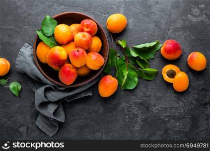 Fresh apricots with leaves and dried in bowl on table