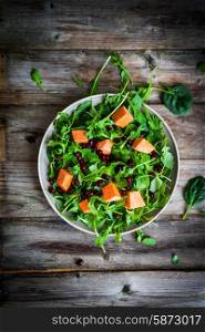 Fresh arugula and spinach salad with pumpkin on rustic background