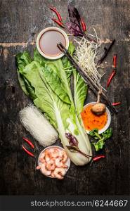 Fresh asian cooking ingredients with rice noodles and shrimps. Asian food vegetables and sauces.