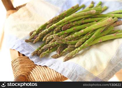 Fresh asparagus on a damaged old chair with a pastel cotton napkin