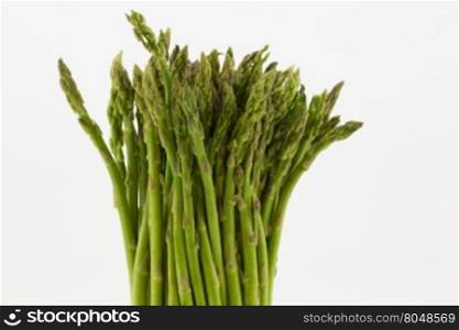 Fresh asparagus stalks in upright position agains white background. Horizontal image with copy space on right.