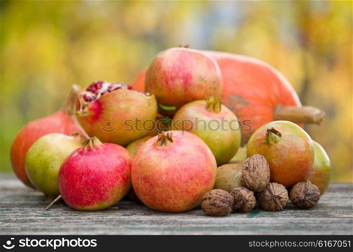 Fresh autumn fruits, apples and pomegranates, on a wooden table
