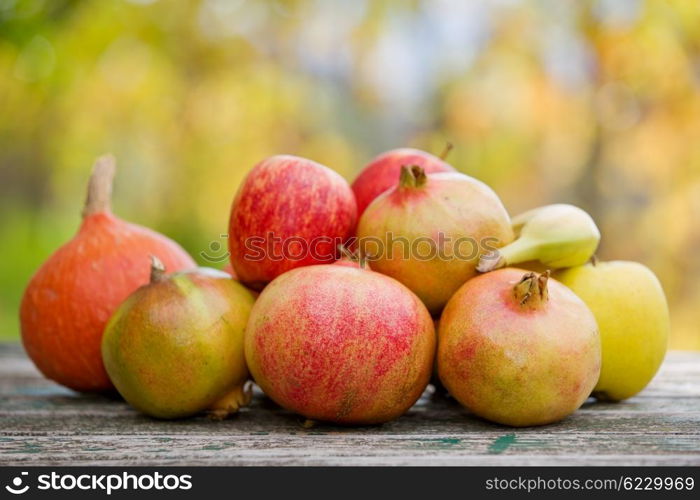 Fresh autumn fruits, apples, pomegranate and banana, on a wooden table