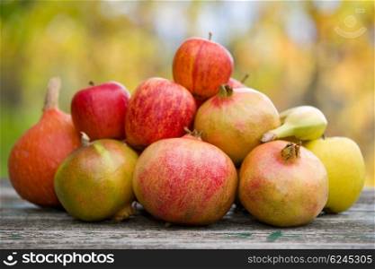 Fresh autumn fruits, apples, pomegranate and banana, on a wooden table
