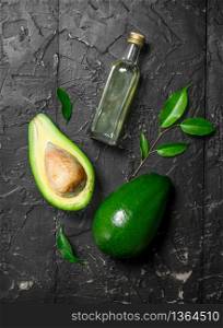Fresh avocado and a bottle. On black rustic background.. Fresh avocado and a bottle.