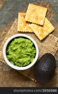 Fresh avocado cream or guacamole with soda crackers on the side, photographed overhead with natural light (Selective Focus, Focus on the top of the avocado cream)