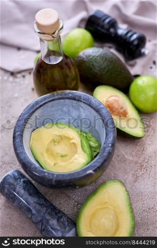 fresh avocado cut in half and marble mortar on grey concrete table.. fresh avocado cut in half and marble mortar on grey concrete table