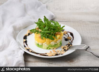 Fresh avocado, mango, mozzarella and arugula salad seasoned with nuts