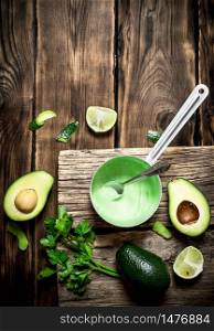 Fresh avocado sauce, lime and herbs. On wooden background.. Fresh avocado sauce, lime and herbs.