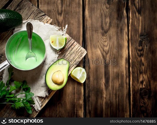 Fresh avocado sauce, lime and herbs. On wooden background.. Fresh avocado sauce, lime and herbs.