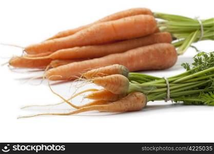 Fresh baby carrots and large ones to see the difference in size close up on white background